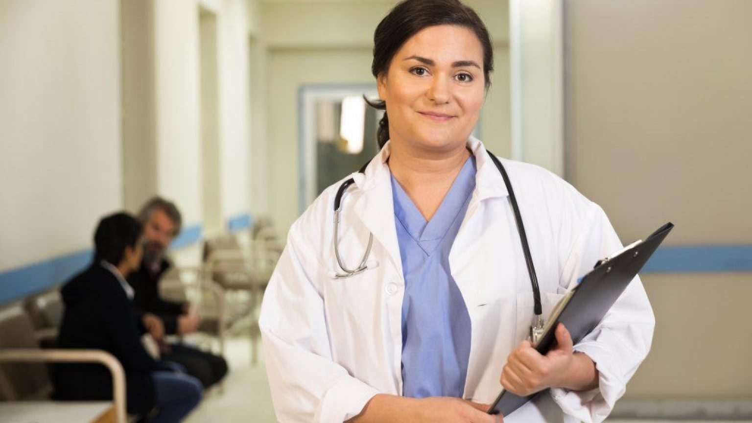 A doctor smiles while holding her clipboard 1024x683